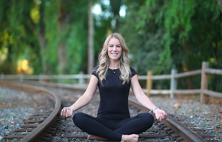 Smiling woman meditating on railroad tracks
