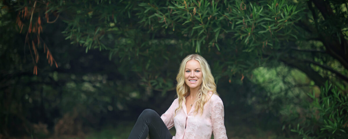 Smiling woman sitting on grass under trees
