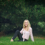 Smiling woman sitting on grass under trees