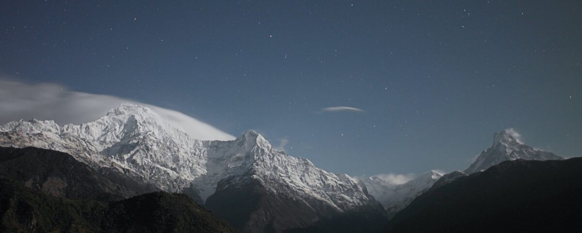 Snow-capped mountains under starry night sky