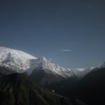Snow-capped mountains under starry night sky